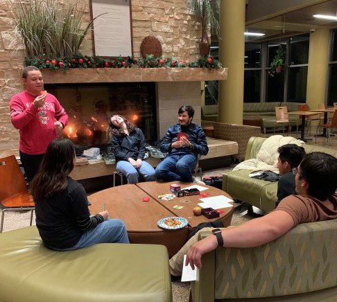 College age young adults playing a card game in a community space on campus.